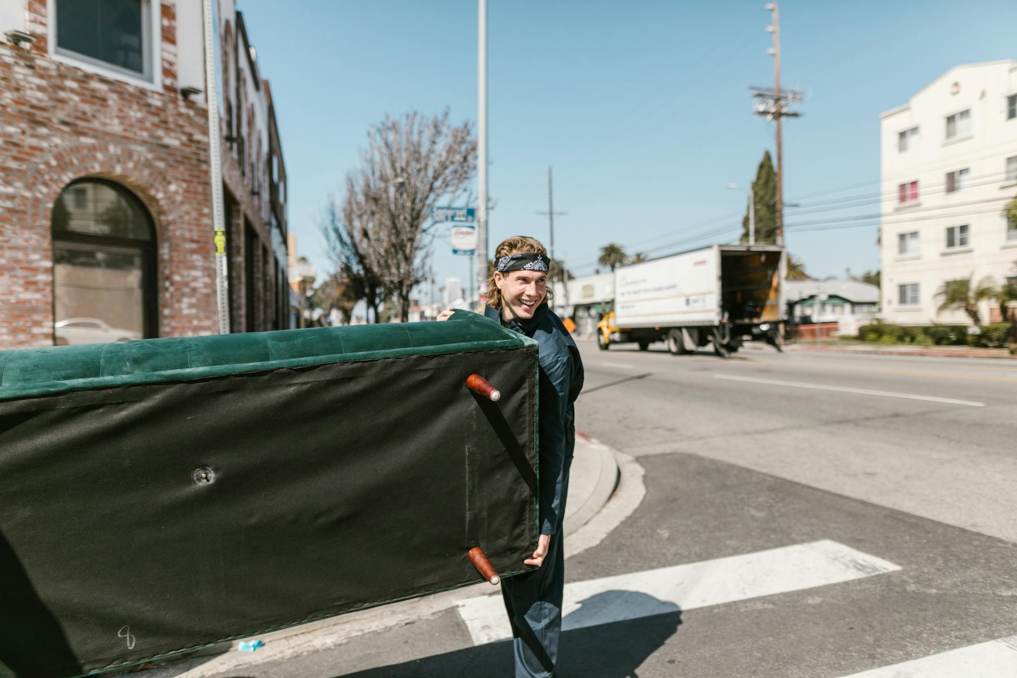 a cheerful man carries a large couch